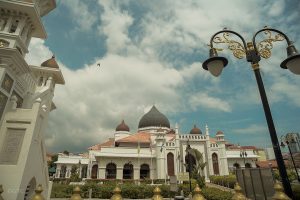 a white coloured mosque with a dome and blue skies