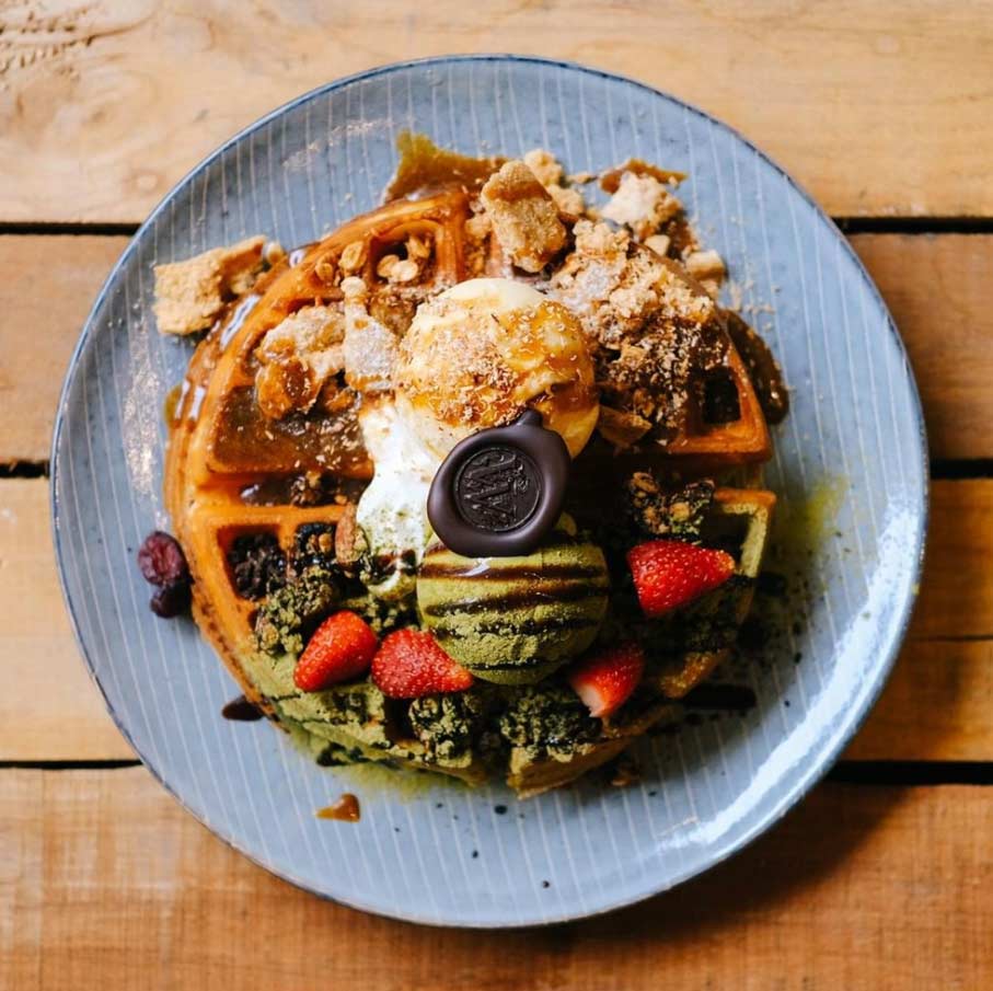 waffle topped with ice cream, strawberries and granolas