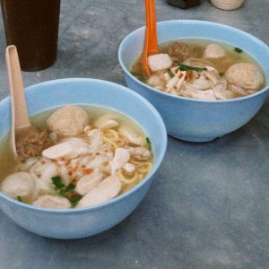two bowls of noodles and fish balls with broth