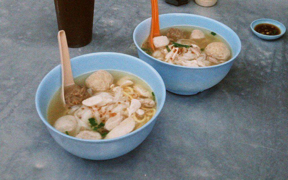 two bowls of noodles and fish balls with broth