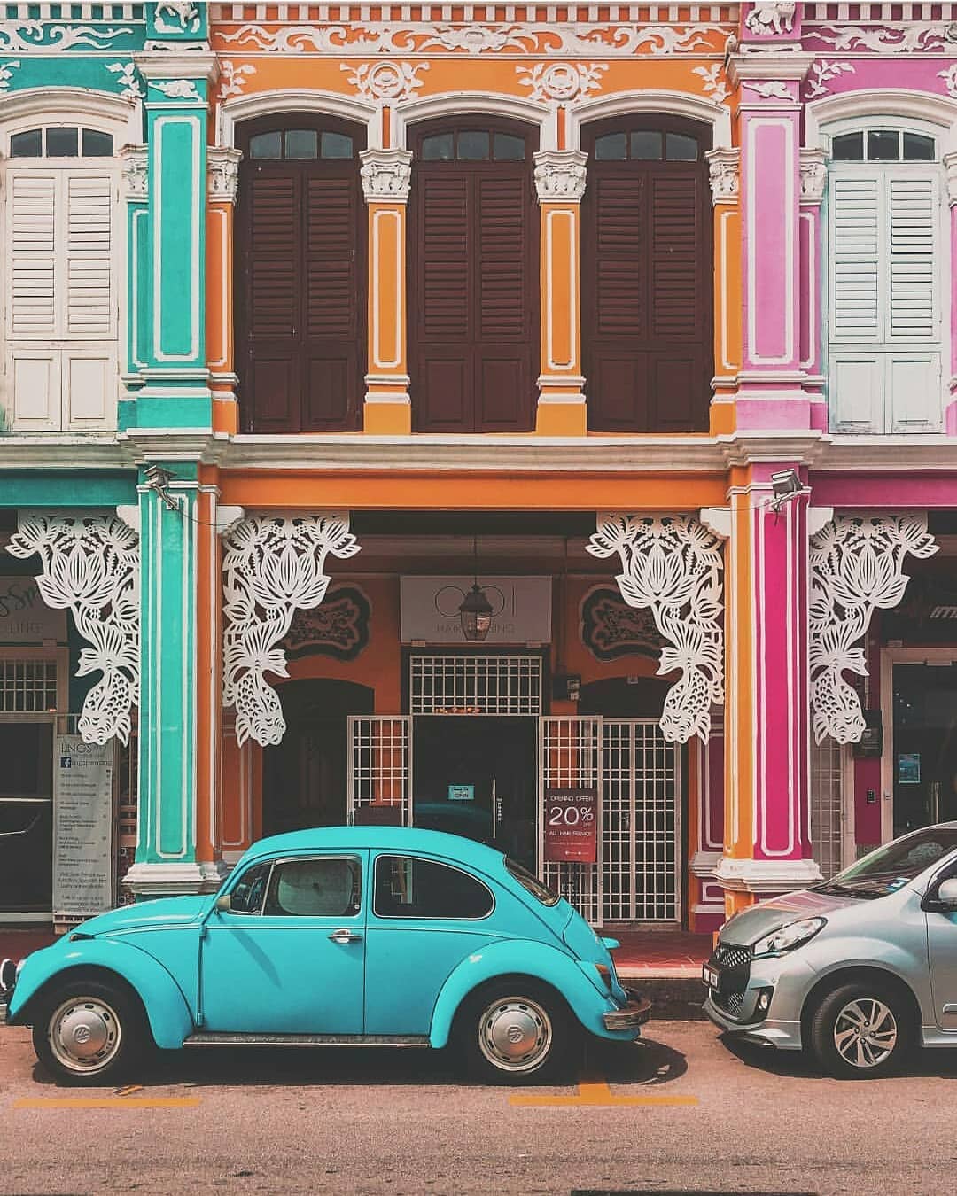 cars parked outside of a row of colourful heritage houses