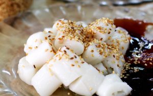 Steamed flat rice rolls served with prawn paste, sweet sauce and chilli on a plate
