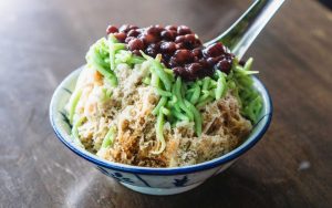a shaved iced dessert with red azuki beans served in a traditional bowl