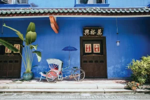 trishaw in front of a building with indigo colours walls and traditional wooden door with Chinese wordings