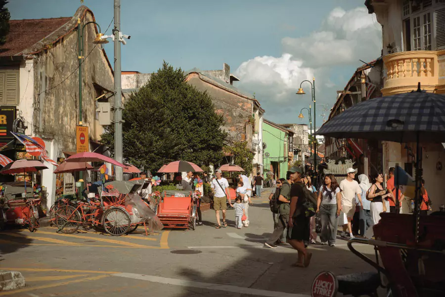 crowds walking around an old heritage street filled with trishaws