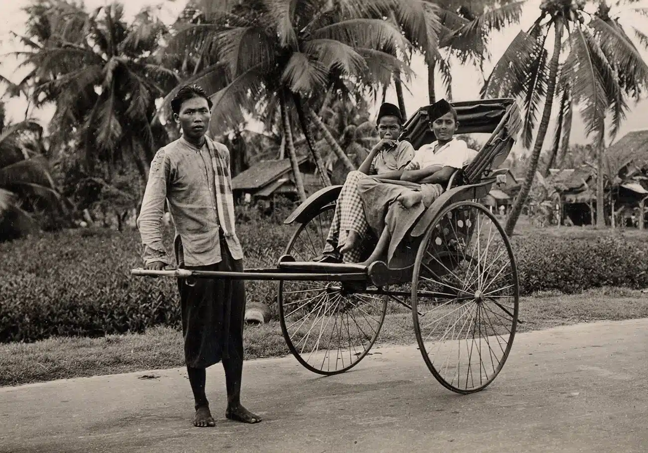 a man pulling a trishaw with kids sitting on it