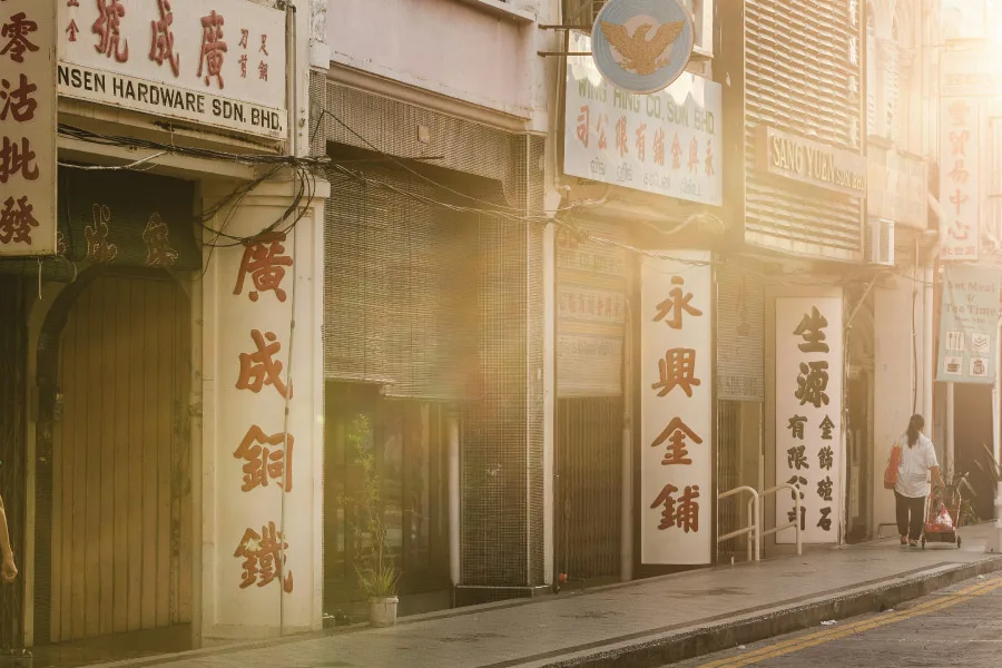 natural light shining towards the facade of old shophouses along a street