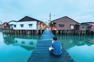 a man sitting on a wooden jetty with wooden houses along