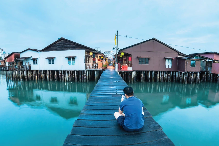 a man sitting on a wooden jetty with wooden houses along