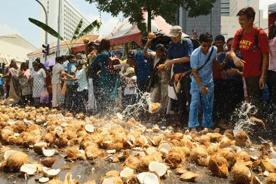 people throwing and breaking coconuts by the streets