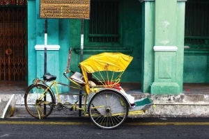 yellow colour trishaw parked by the street beside an old rustic building