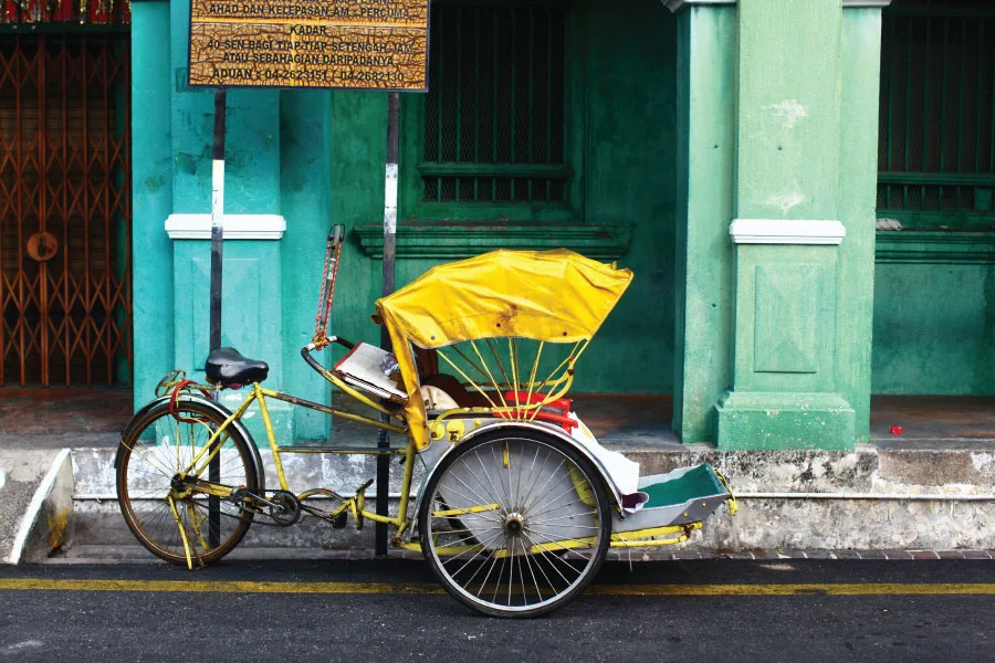 yellow colour trishaw parked by the street beside an old rustic building