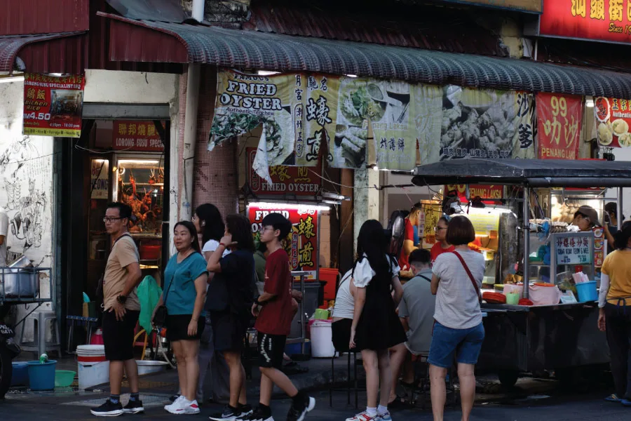 people queueing for food at a stall by the street