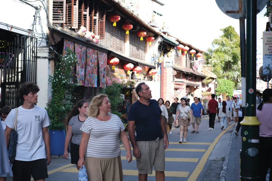 crowds walking along a street with old houses