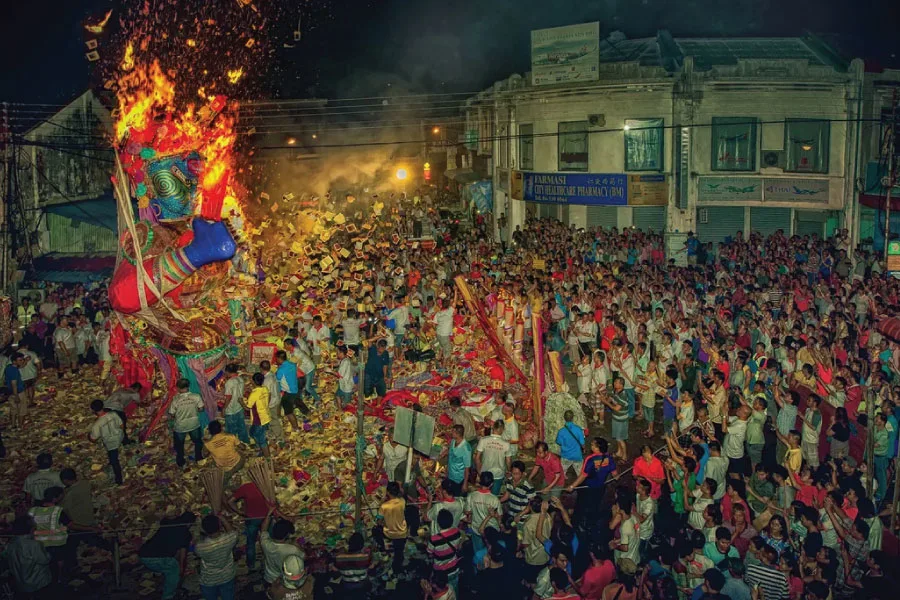 crowds surrounding a paper effigy that is being burnt
