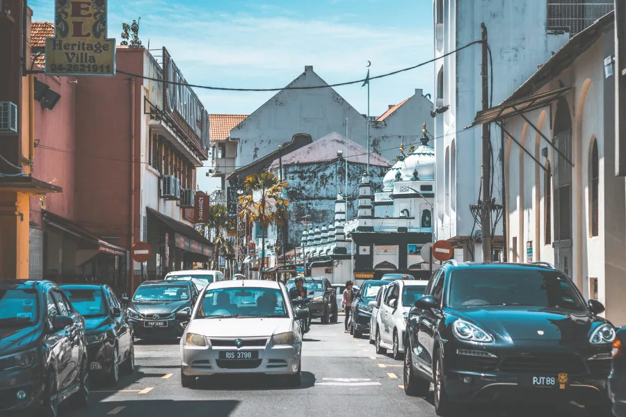 cars along a narrow street with old buildings by the sides