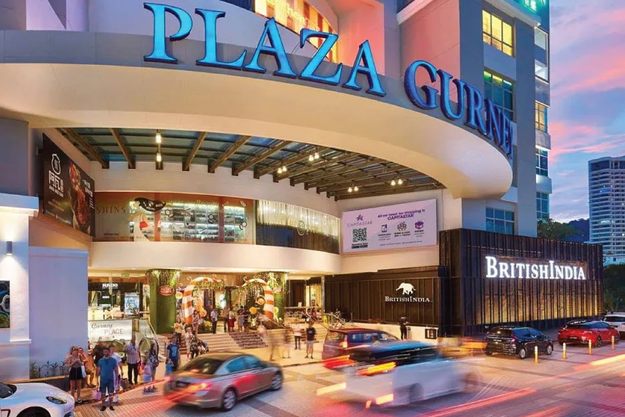 a facade of a shopping mall with cars passing by