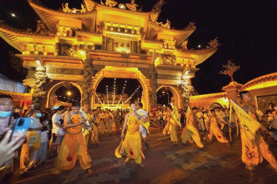 people performing ritual in front of temple with traditional Chinese architecture